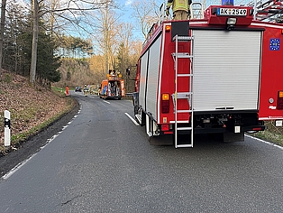 Feuerwehrauto und Straßenmeisterei bei einem Einsatz, wo ein Baum auf eine Straße gefallen ist