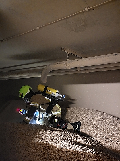 Feuerwehrmann in persönlicher Schutzausrüstung unter Atemschutz in einem Pelletbunker