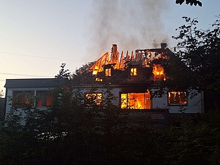Ein teilweise abgebranntes Haus, aus dem Flammen schlagen