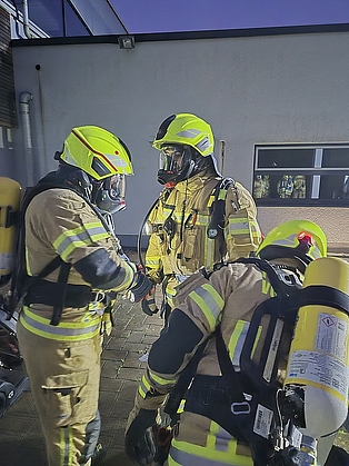 Drei Feuerwehrleute, die mit Atemschutz aufgerüstet sind