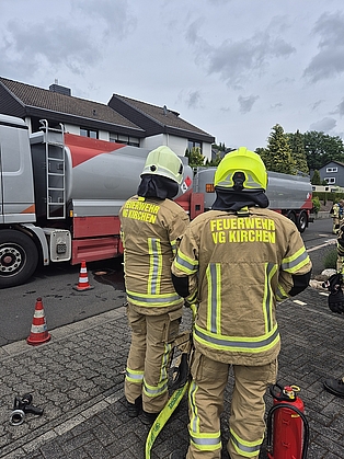 Feuerwehrleute mit einem Strahlrohr, die neben einem Heizöl-LKW stehen