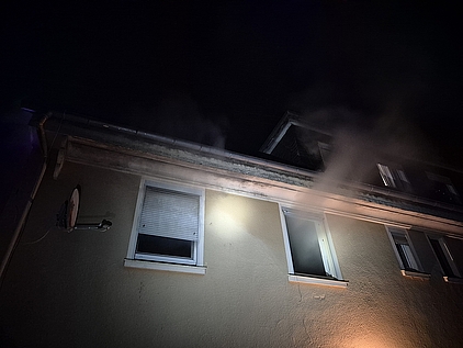 Eine Hausfassade mit mehreren Fenstern, aus denen Rauch ausdringt