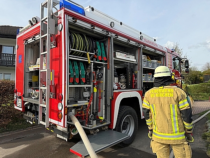 Feuerwehrmann in Schutzkleidung neben einem Feuerwehrauto