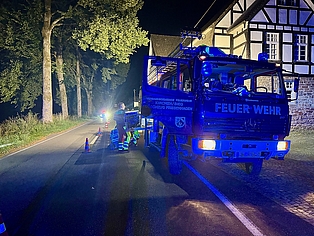 Ein Feuerwehrauto, dass beleuchtet und mit Blaulicht auf einer abgesperrten Straße steht